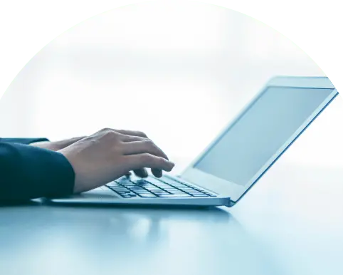 ノートパソコンに向かってタイピングする手元のアップ、背景は明るい室内