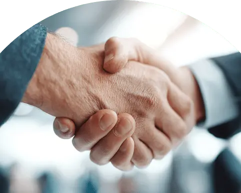 背景がぼやけた場所でがっちりと握手する二人の手元、ビジネス合意の象徴的場面